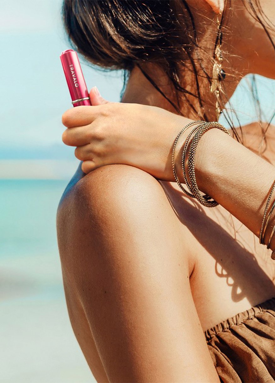 Woman holding Travalo product on the beach